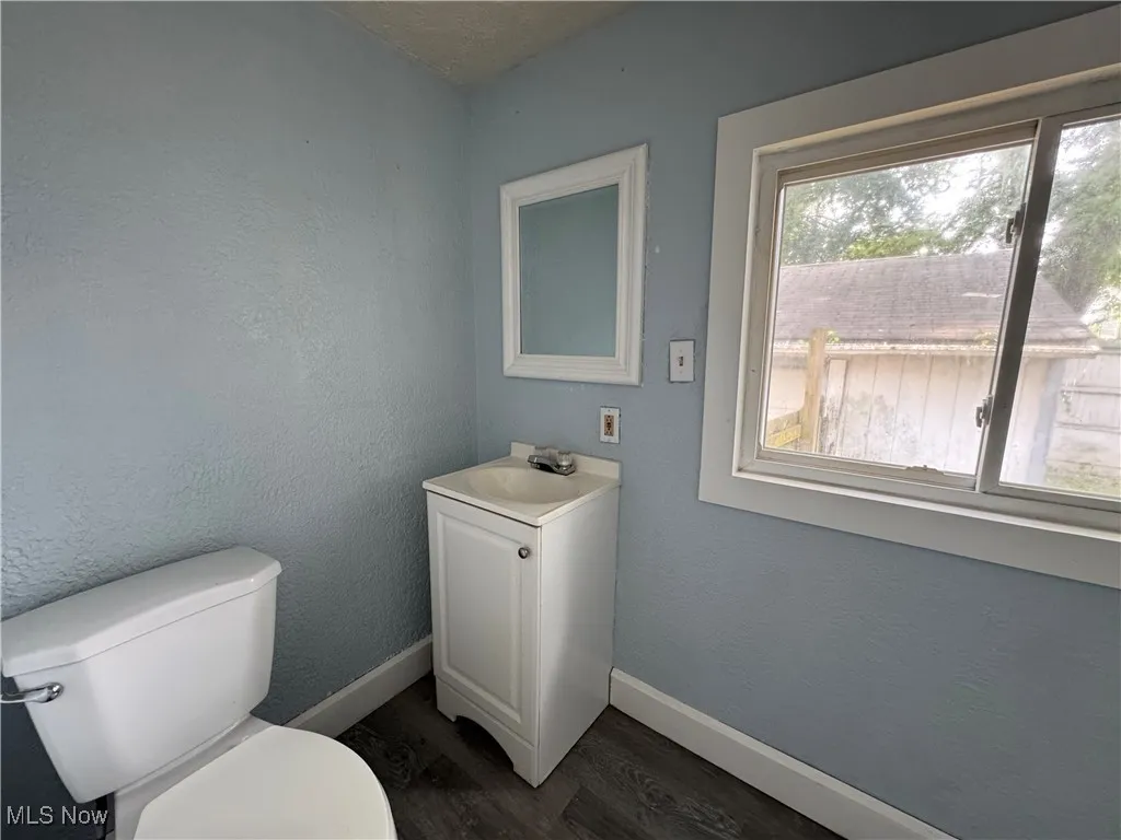 Main Floor Full Bathroom featuring vanity, dark wood-style flooring, a textured wall, and a textured ceiling