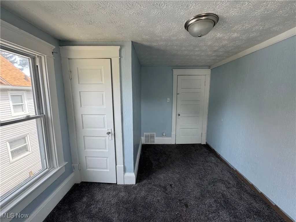 Bedroom 1 featuring dark carpet, a closet, and a textured ceiling