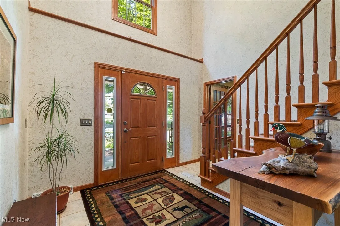 Entryway with healthy amount of natural light, light tile patterned flooring, and a high ceiling