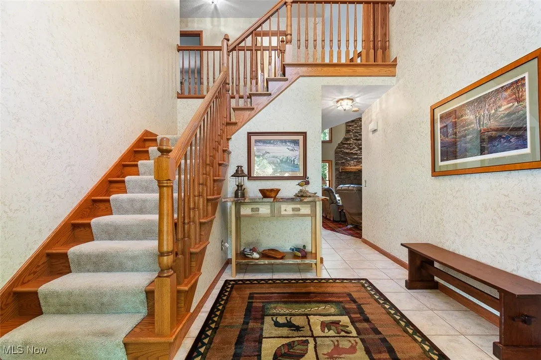 Staircase with a high ceiling, tile patterned floors, wallpapered walls, and a fireplace