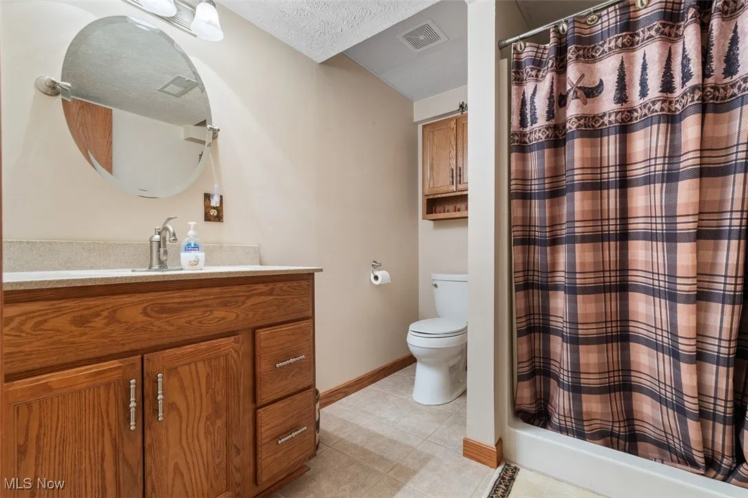 Bathroom featuring vanity, light tile patterned flooring, a shower stall, and a textured ceiling