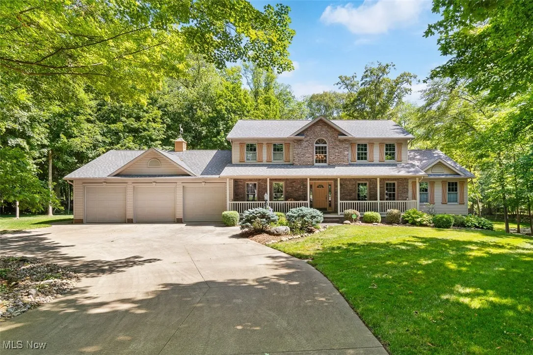 Colonial-style house with a porch, a front yard, driveway, a garage, and a chimney