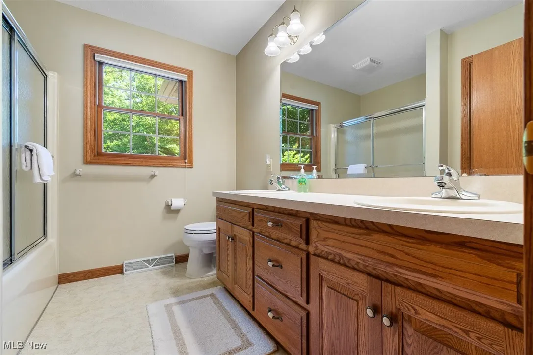 Full bath featuring double vanity and shower / bath combination with glass door
