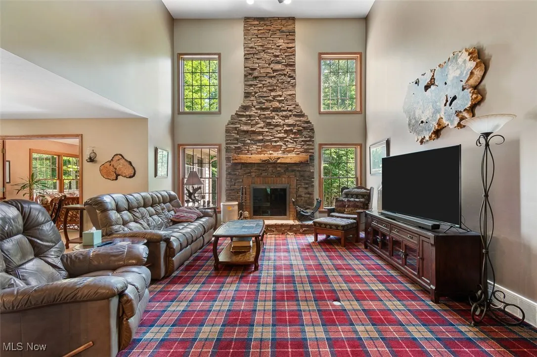 Living area with a towering ceiling and a stone fireplace