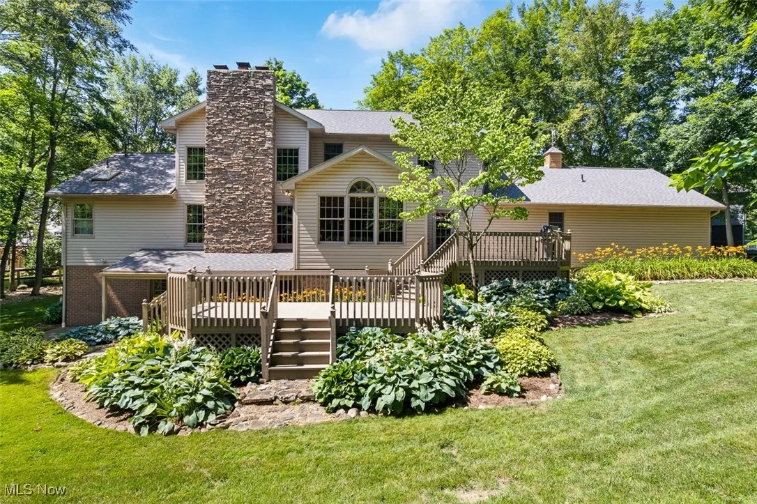 Rear view of property with a deck, a chimney, and a lawn