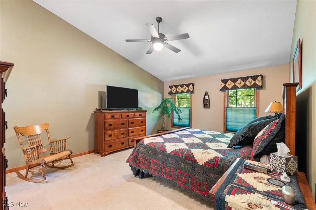 Bedroom featuring lofted ceiling, light carpet, and a ceiling fan