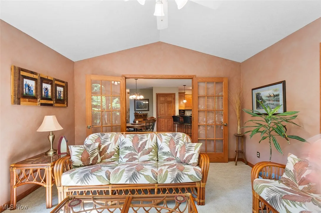 Carpeted sunroom featuring vaulted ceiling, a chandelier, and ceiling fan