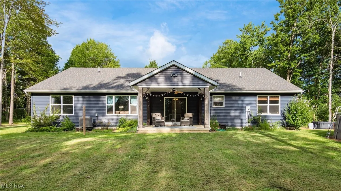 Rear view of property featuring a ceiling fan, a yard, and a wooden deck