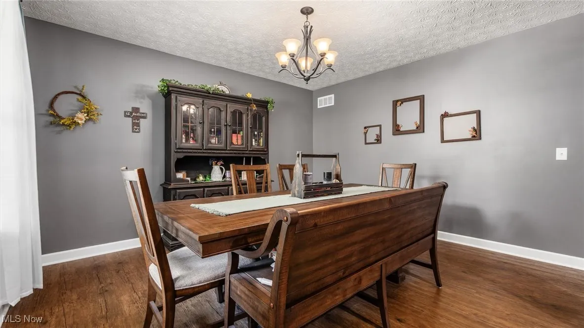 Dining space featuring a chandelier, dark wood finished floors, and a textured ceiling