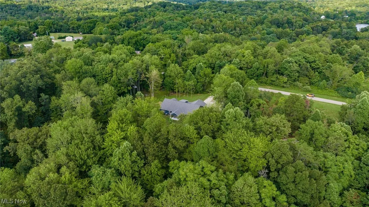 Aerial view of property and surrounding area featuring a heavily wooded area
