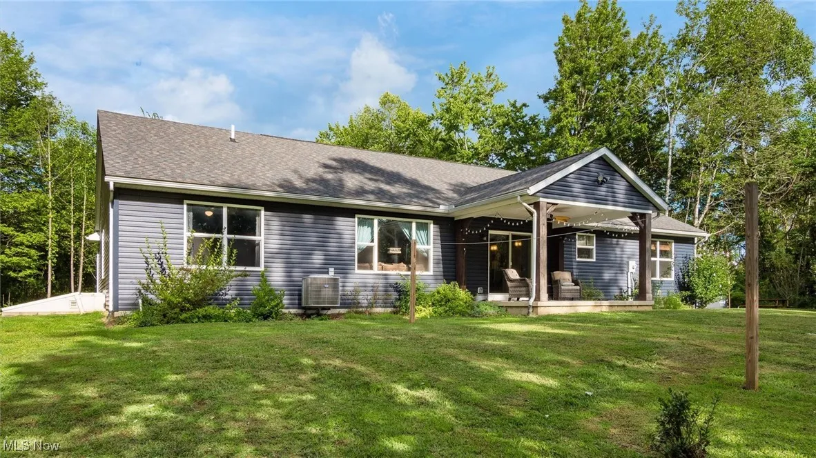 Back of house with a lawn and roof with shingles