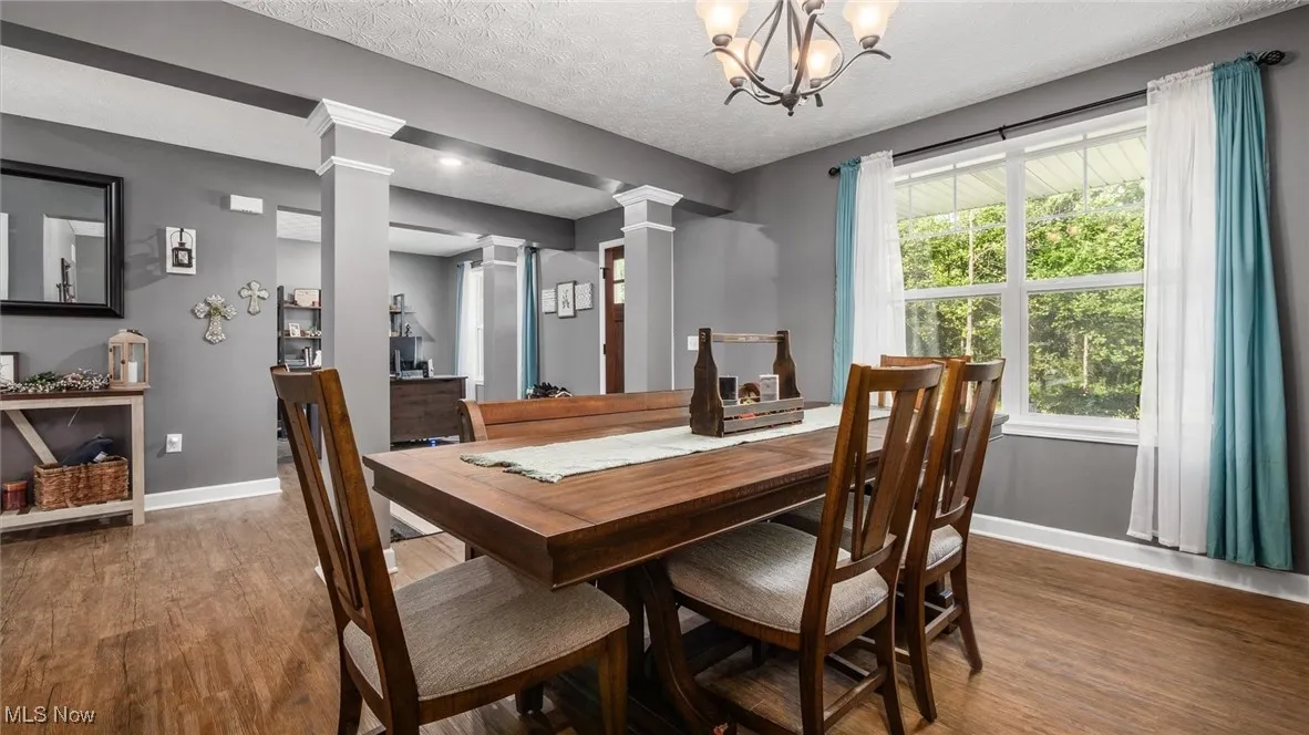 Dining area featuring ornate columns, wood finished floors, and a textured ceiling