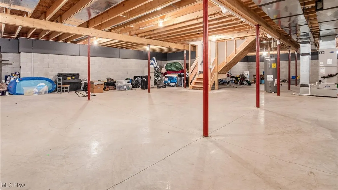 Unfinished below grade area featuring stairs, heating unit, and water heater