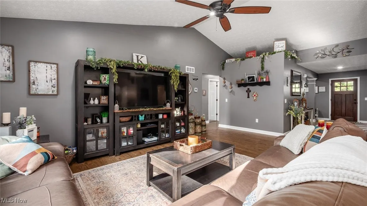 Living area with wood finished floors, vaulted ceiling, ceiling fan, and a textured ceiling