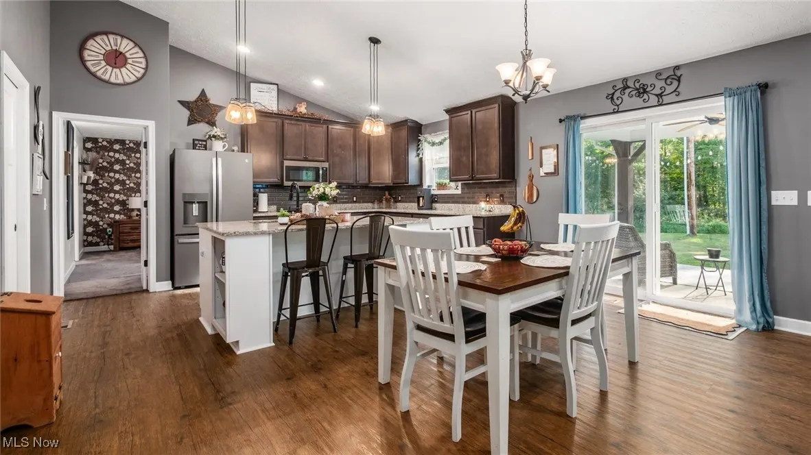 Dining space featuring vaulted ceiling, dark wood-style floors, recessed lighting, and a chandelier