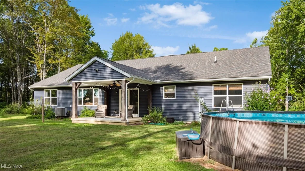 Rear view of property featuring a wooden deck, a lawn, roof with shingles, and a ceiling fan