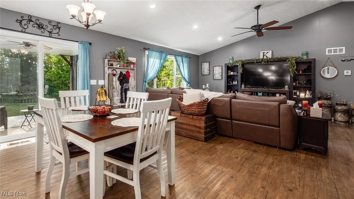 Dining room with a ceiling fan, lofted ceiling, wood finished floors, recessed lighting, and a chandelier