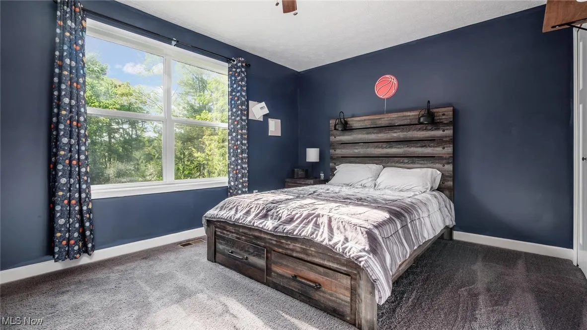 Carpeted bedroom featuring ceiling fan and baseboards