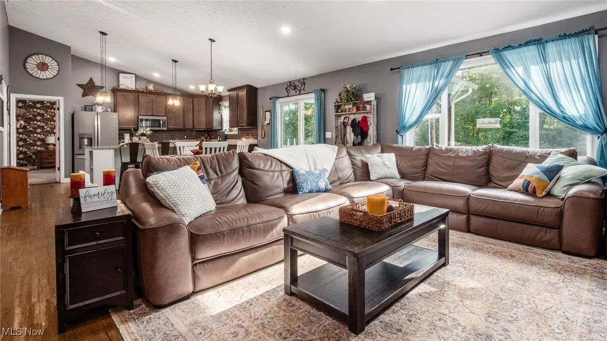 Living area with a chandelier, vaulted ceiling, recessed lighting, and dark wood finished floors