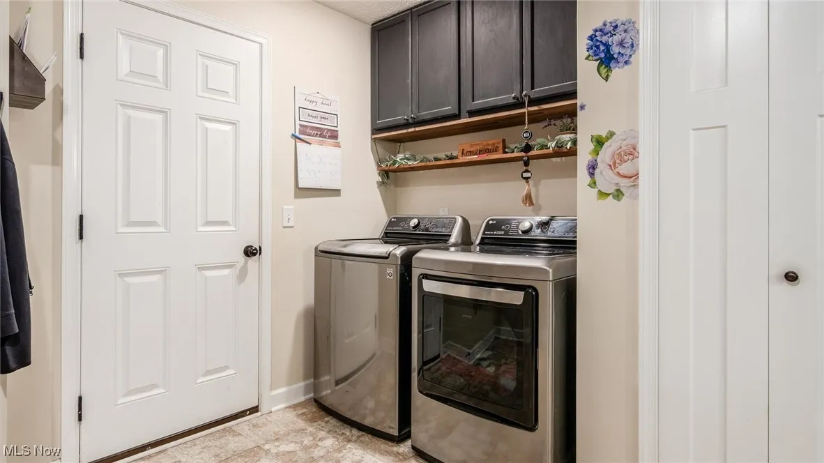 Laundry room featuring washer and dryer, cabinet space, and light tile patterned flooring