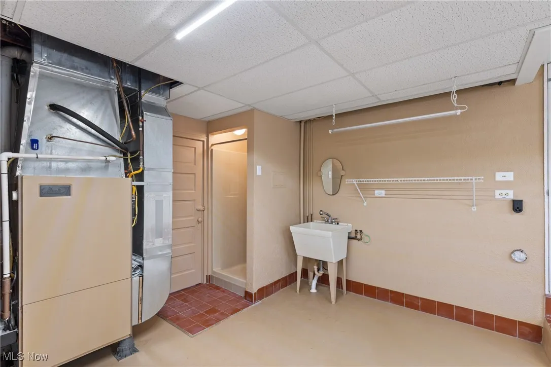 Finished below grade area with a paneled ceiling and heating unit