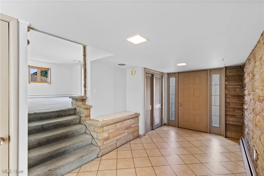 Entrance foyer featuring light tile patterned floors and baseboard heating