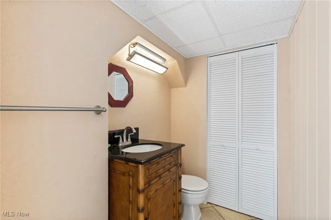 Bathroom featuring vanity, a closet, light tile patterned flooring, and a paneled ceiling