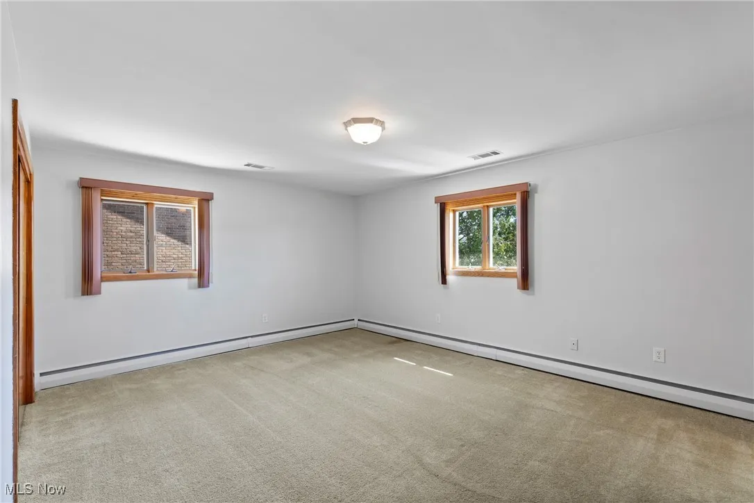 Spare room featuring light carpet and baseboard heating