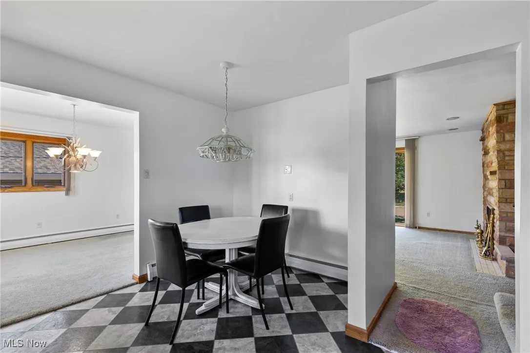 Dining area featuring dark carpet, a baseboard radiator, and a chandelier