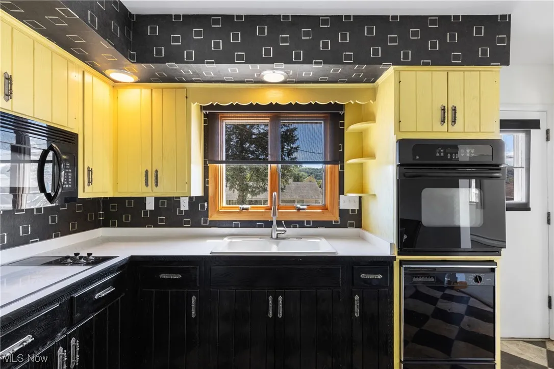 Kitchen featuring black appliances, decorative backsplash, light countertops, open shelves, and beverage cooler