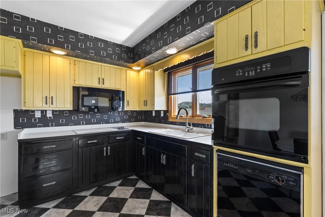 Kitchen featuring light flooring, black appliances, light countertops, and decorative backsplash