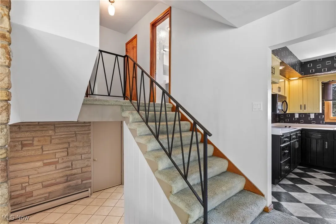 Stairs with a baseboard radiator and tile patterned floors
