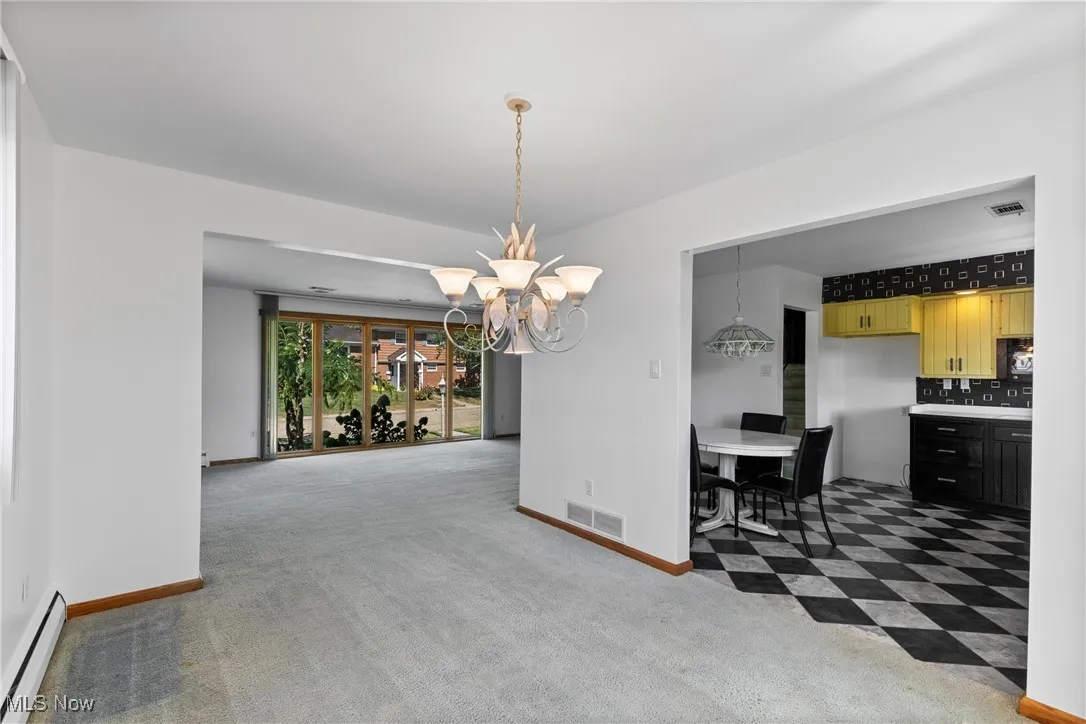 Dining room with light carpet, baseboard heating, and a chandelier