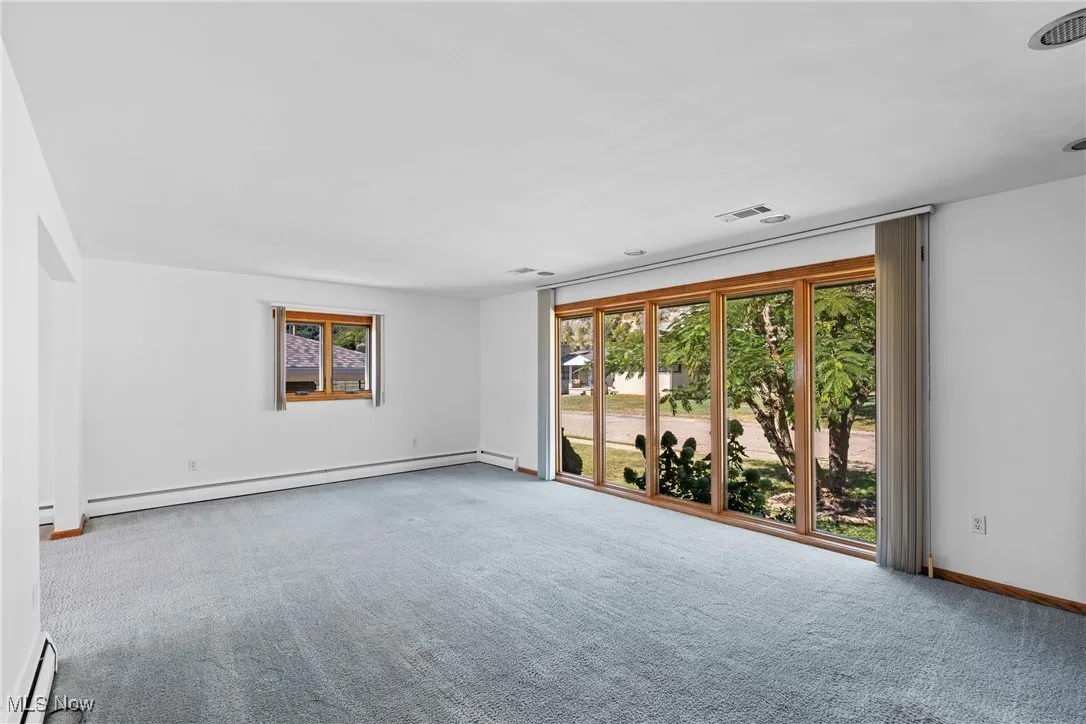 Unfurnished room featuring a baseboard heating unit and carpet flooring