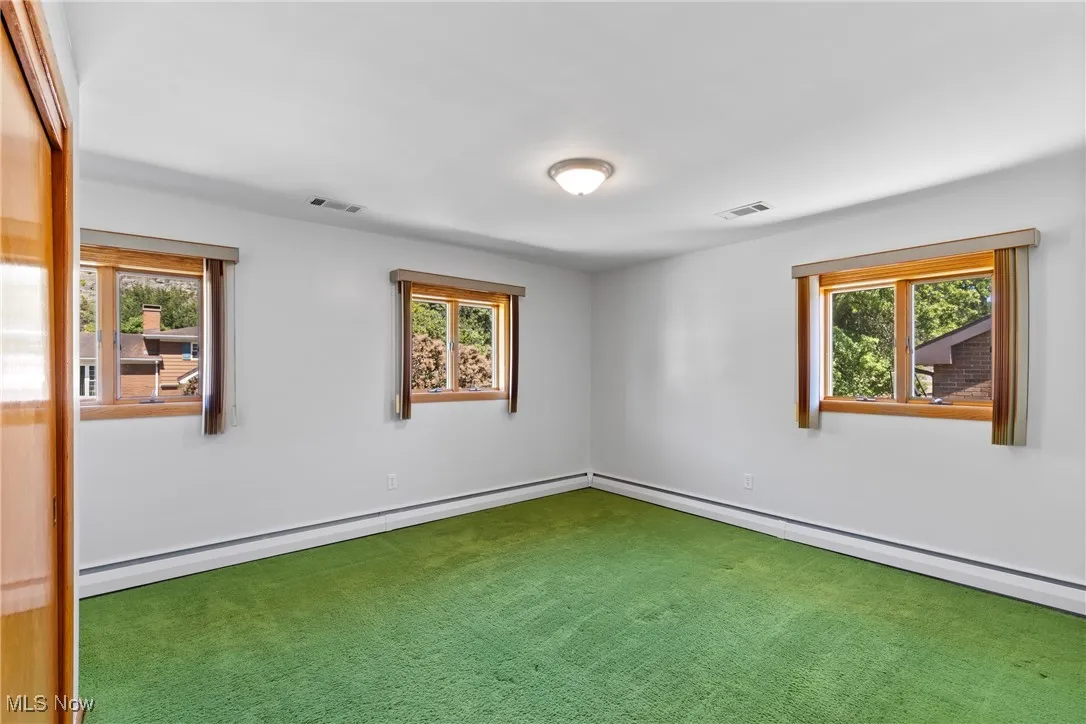 Carpeted empty room with plenty of natural light and a baseboard heating unit
