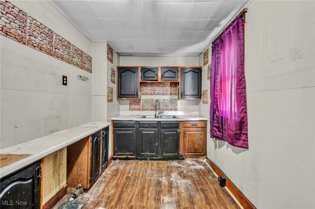 Bar with dark wood-type flooring, light countertops, and tasteful backsplash