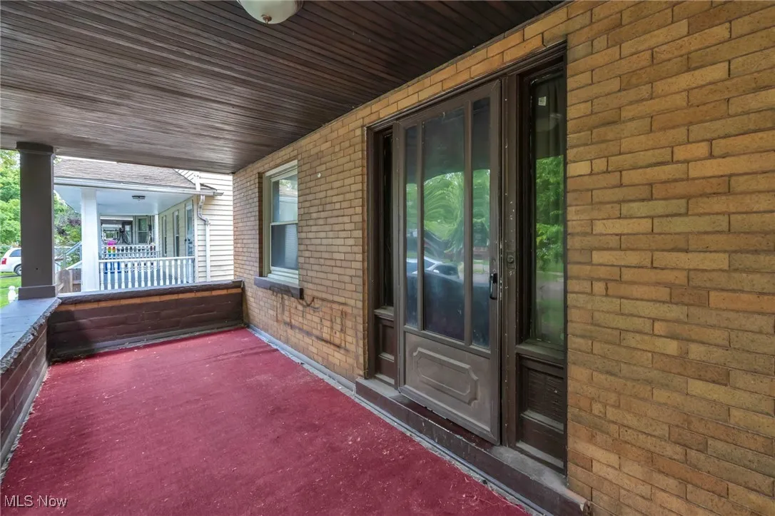 Doorway to property with a porch and brick siding