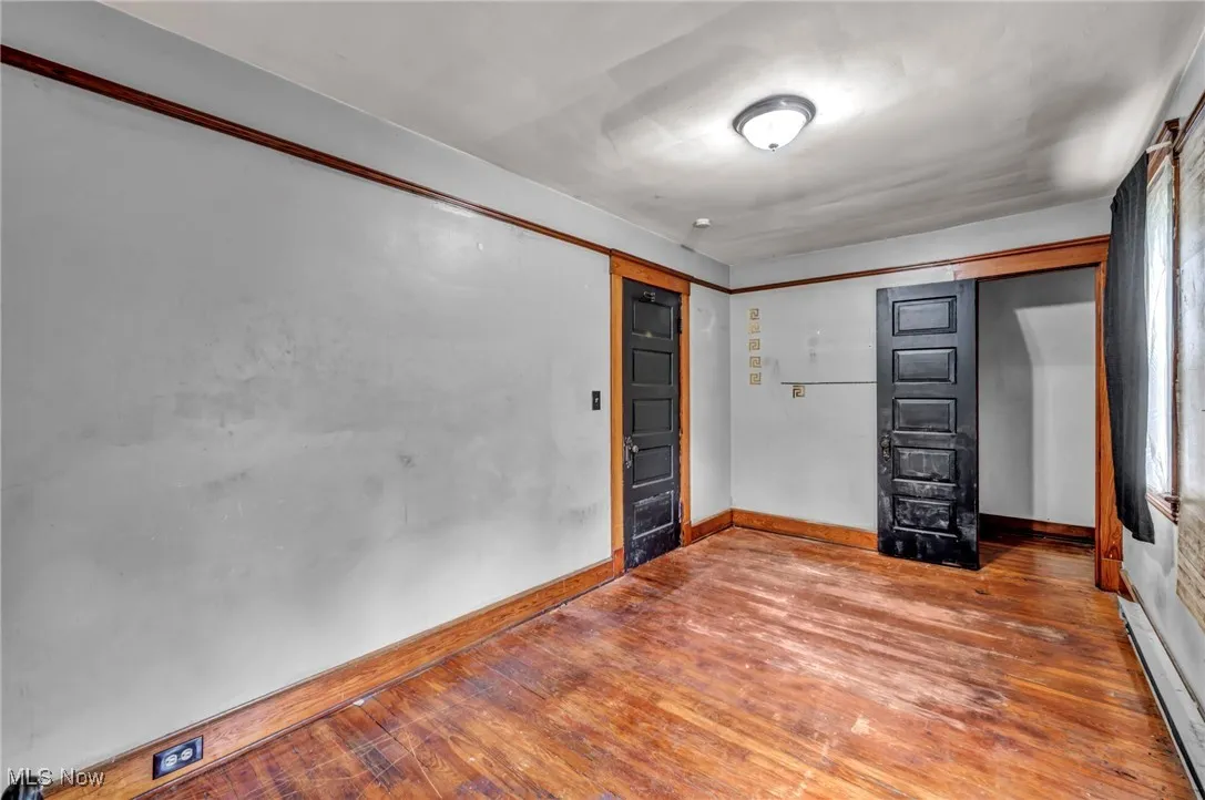 Unfurnished bedroom featuring hardwood / wood-style floors and a baseboard radiator