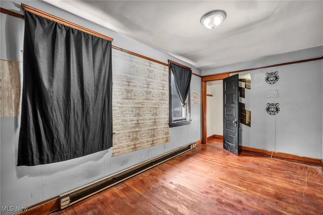 Unfurnished room featuring wood-type flooring and a baseboard radiator