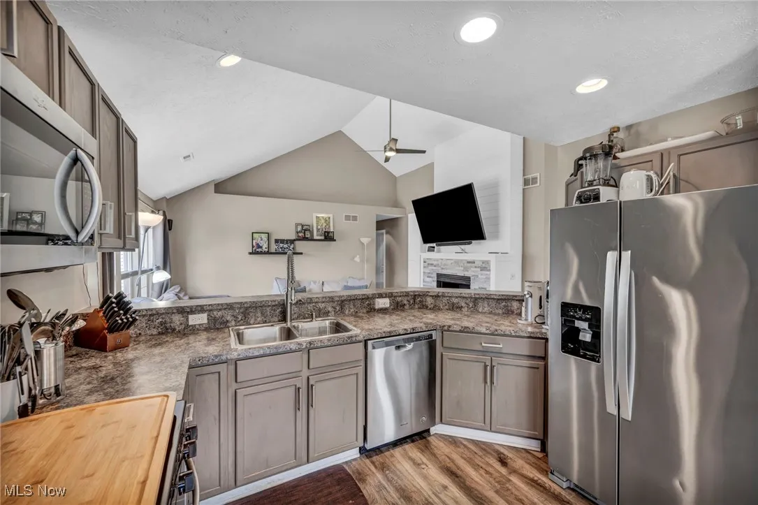 Kitchen featuring appliances with stainless steel finishes, vaulted ceiling, open floor plan, gray cabinets,