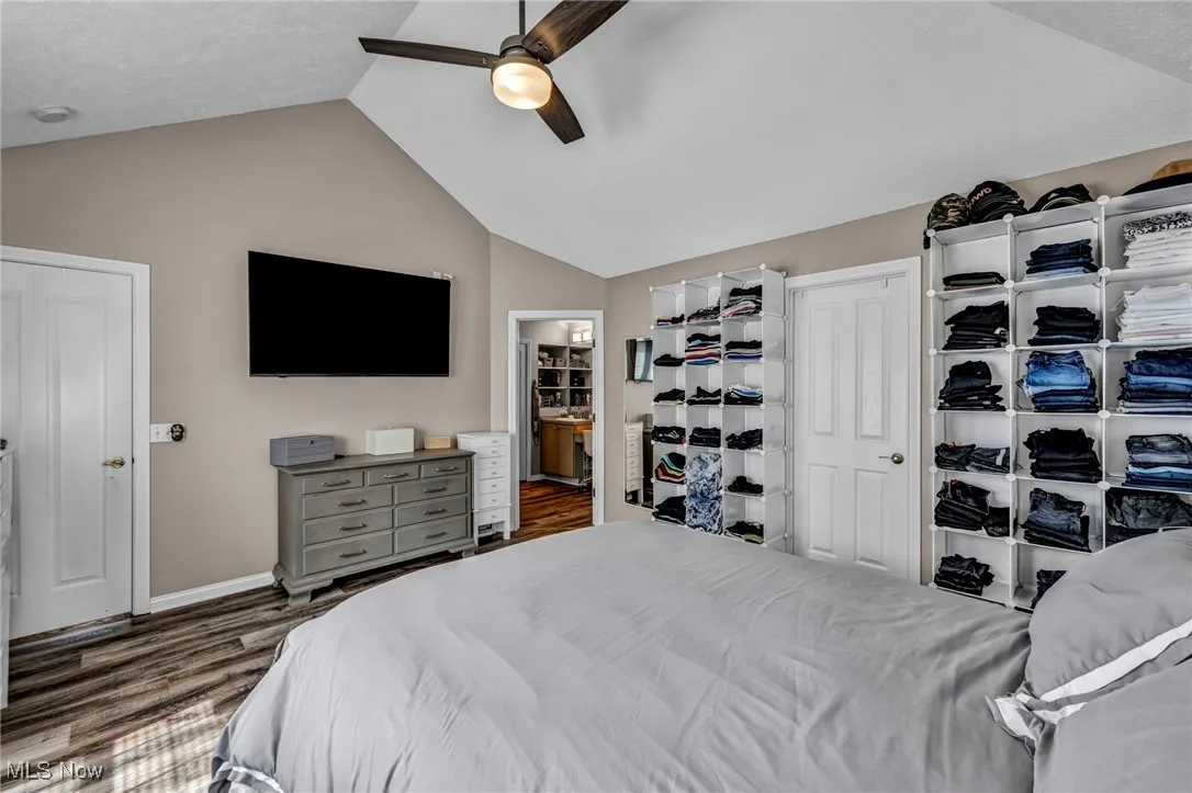 Bedroom with dark wood-type flooring, vaulted ceiling, and a ceiling fan