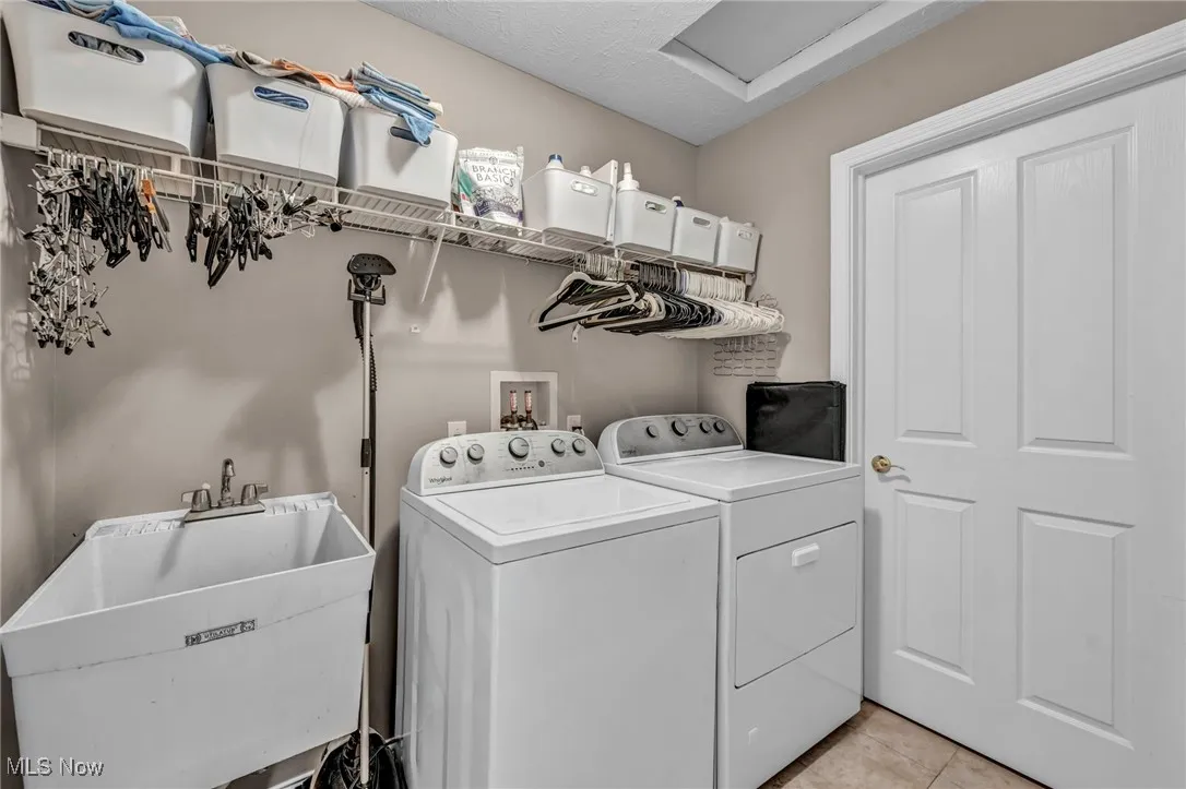 Laundry room featuring washer and dryer, light tile patterned flooring, large closet for storage