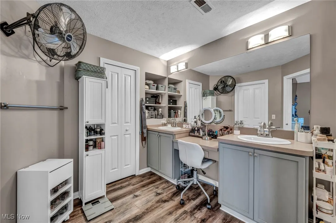 Full bath featuring a textured ceiling, double vanity, and dark wood-type flooring