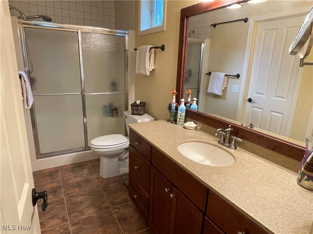 Full bathroom featuring vanity, a stall shower, and dark tile patterned flooring