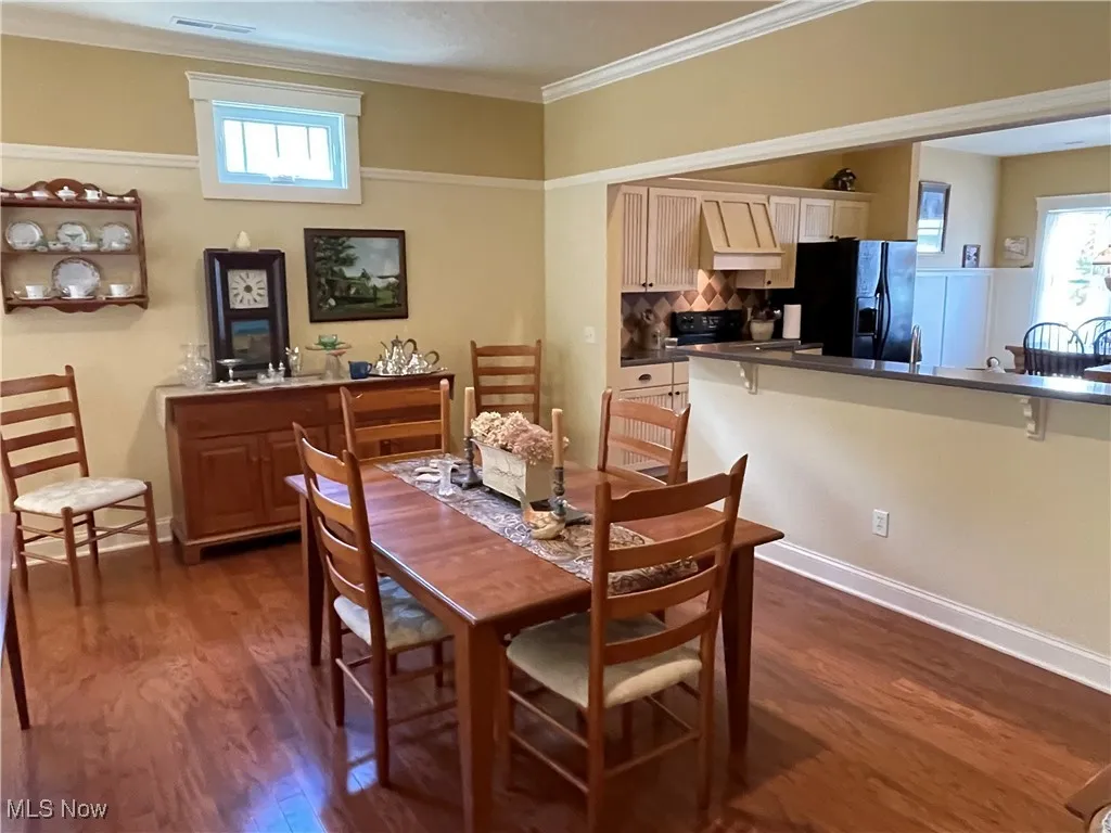 Dining room featuring dark wood-style floors, plenty of natural light, and ornamental molding