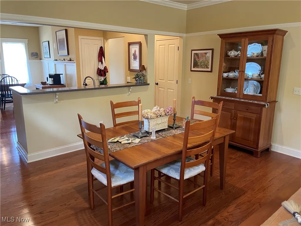 Dining room featuring dark wood finished floors and crown molding