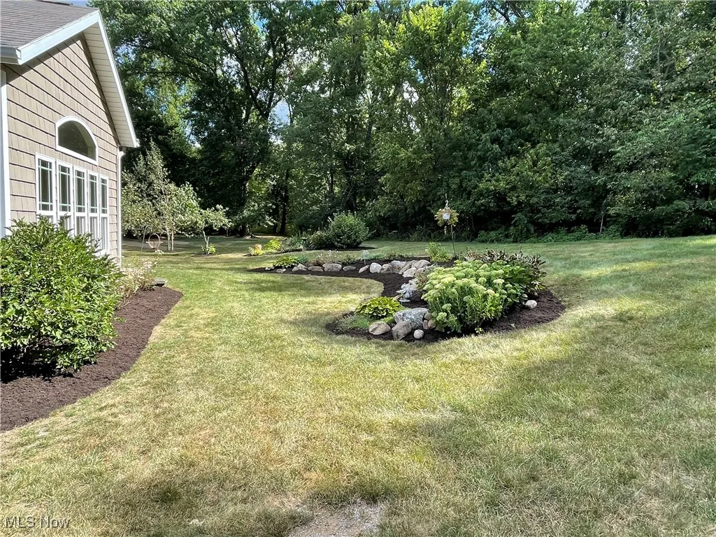 View of grassy yard featuring view of wooded area