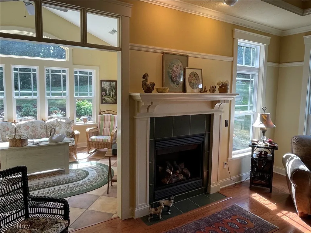 Living area with ornamental molding, a tile fireplace, and wood finished floors