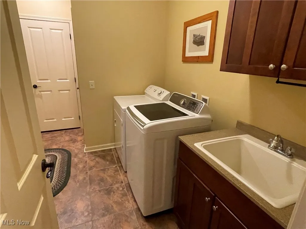 Washroom with independent washer and dryer, cabinet space, and dark tile patterned flooring