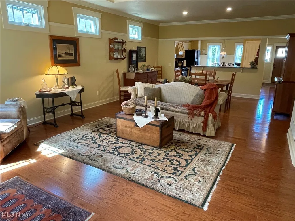 Living area with plenty of natural light, wood finished floors, and ornamental molding